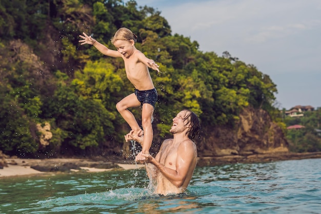 Padre e figlio che giocano sulla spiaggia durante il giorno