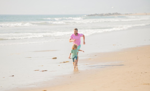 Padre e figlio che si rincorrono sulla spiaggia estiva della famiglia