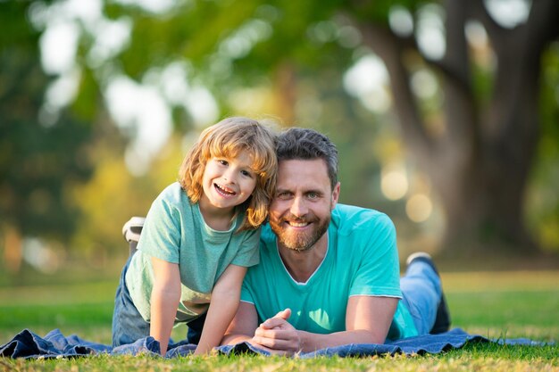 Padre e figlio che sorridono contro lo sfondo sfocato dell'estate al parco