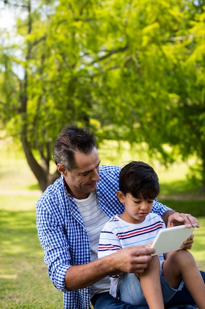 Padre e figlio che utilizza compressa digitale nel parco