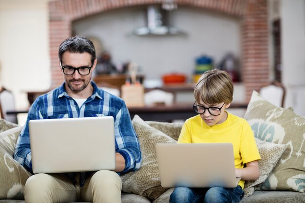 Padre e figlio che utilizza computer portatile nel salone