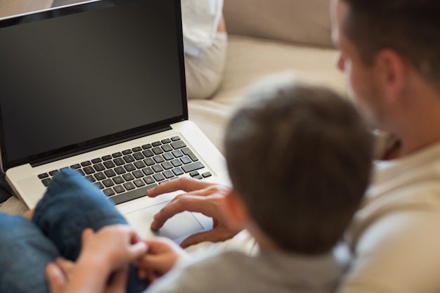 Padre e figlio che utilizza computer portatile nella casa