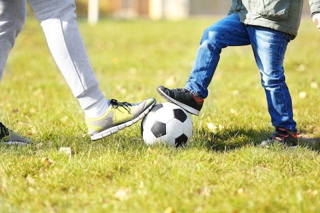 Padre e figlio con la palla sul campo da calcio vista ravvicinata