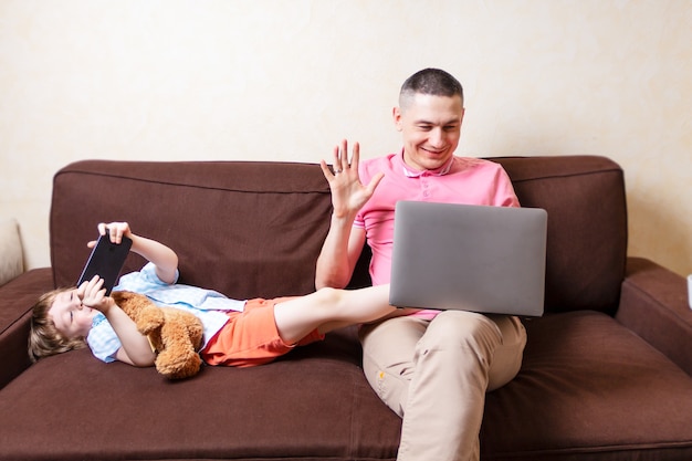 Padre e figlio con laptop e telefono cellulare a casa