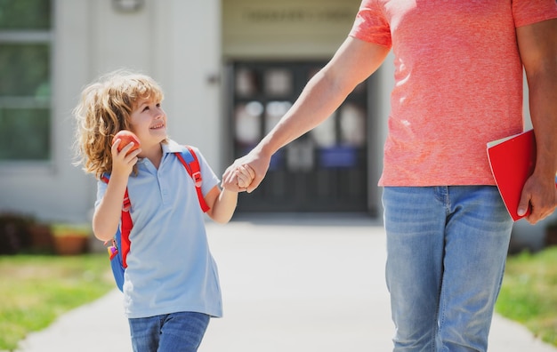 Padre e figlio corrono con il padre tornano da scuola Istruzione familiare e concetto all'aperto Padre che cammina a scuola con il bambino