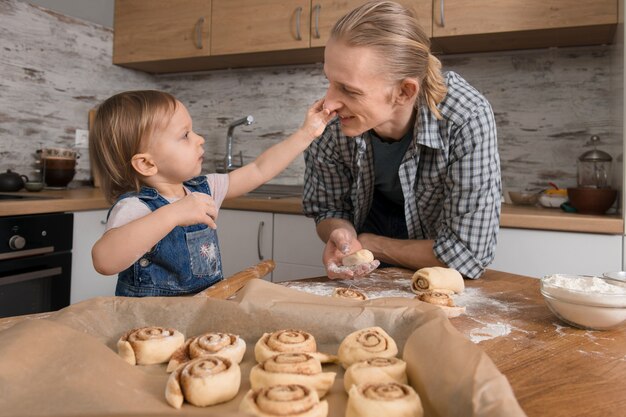 Padre e figlio cuociono i Cinnabons in cucina con divertimento