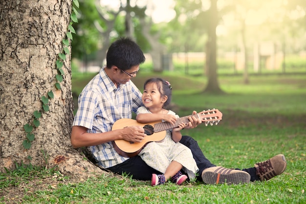 Padre e figlio divertirsi a suonare la chitarra insieme nel parco