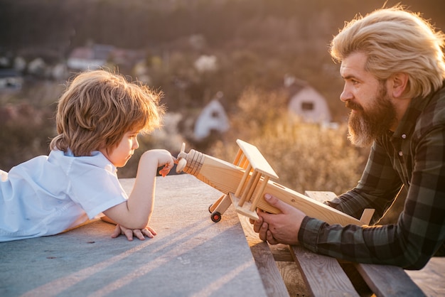 Padre e figlio felici con l'aereo sognano di viaggiare. Papà bambino giorno.