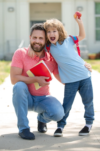 Padre e figlio felici tornano da scuola. Scuola, educazione dei bambini e concetto all'aperto.