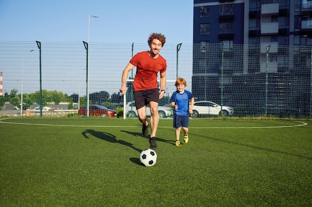 Padre e figlio giocano a calcio sul campo confronto amichevole di genitore e figlio