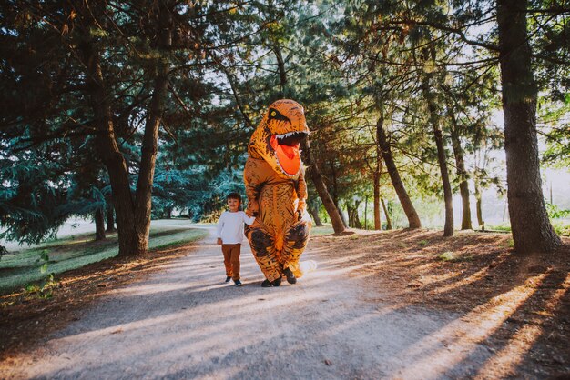 Padre e figlio giocano nel parco, con un costume da dinosauro, divertendosi con la famiglia all'aperto