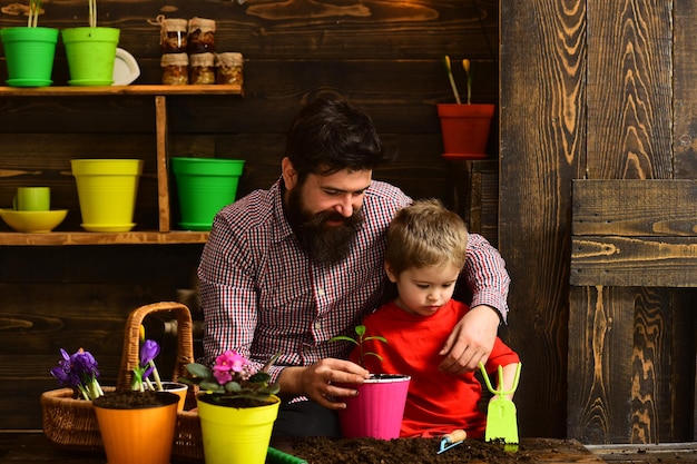 Padre e figlio Giornata della famiglia Giardinieri felici in serra con fiori primaverili Irrigazione per la cura dei fiori Concimi per il terreno Uomo barbuto e bambino bambino amore natura Giardiniere al lavoro