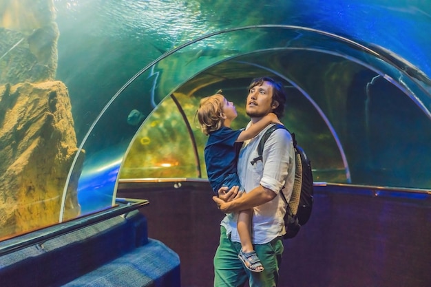 Padre e figlio guardano i pesci nell'acquario in oceanarium.