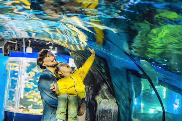 Padre e figlio guardano i pesci nell'acquario nell'oceanario