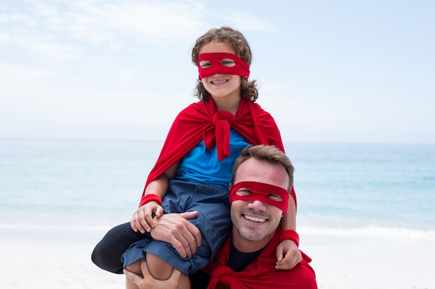 Padre e figlio in costume da supereroe godendo in riva al mare