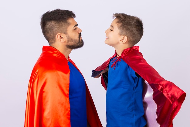 Padre e figlio in costumi da supereroe rosso e blu Padre e figlio che giocano su sfondo bianco in abito da eroe Festa del papà