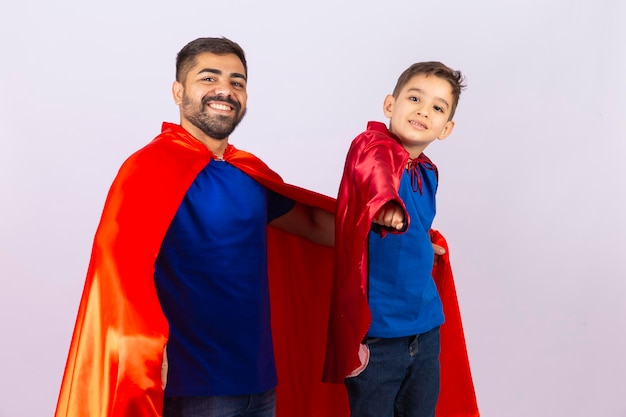 Padre e figlio in costumi da supereroe rosso e blu Padre e figlio che giocano su sfondo bianco in abito da eroe Festa del papà