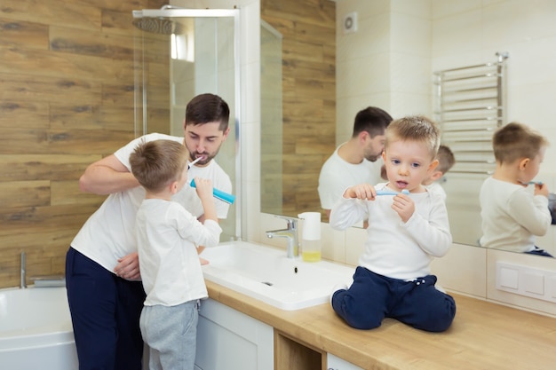 Padre e figlio in giovane età si lavano i denti al mattino, si divertono insieme