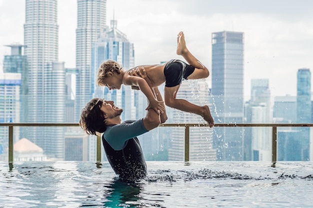 Padre e figlio in piscina all'aperto con vista sulla città nel cielo blu