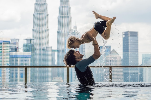 Padre e figlio in piscina all'aperto con vista sulla città nel cielo blu