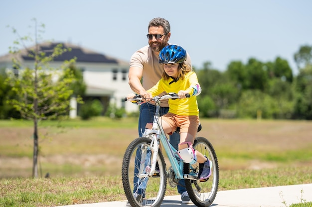 Padre e figlio in un casco in sella a una bici piccolo ragazzo caucasico adorabile carino in casco di sicurezza in sella bi