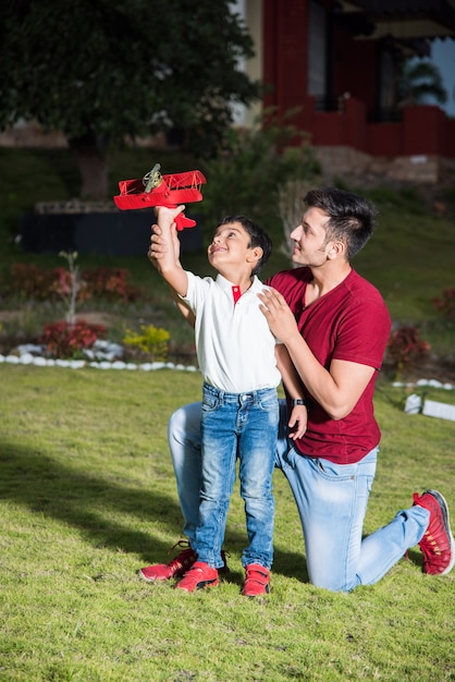 Padre e figlio indiani con aereo giocattolo, all'aperto