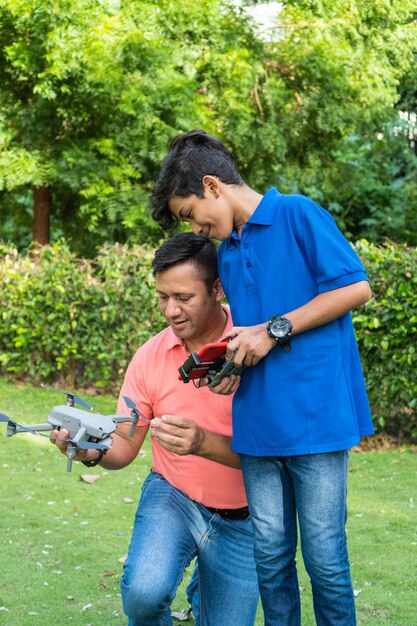 Padre e figlio latino che volano Drone sul campo durante l'estate