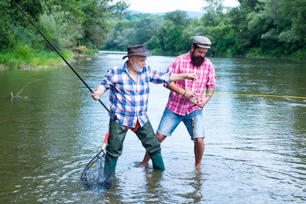 Padre e figlio maturo pescatore pesca con una canna da pesca sul fiume Amici felici eccitati dell'uomo