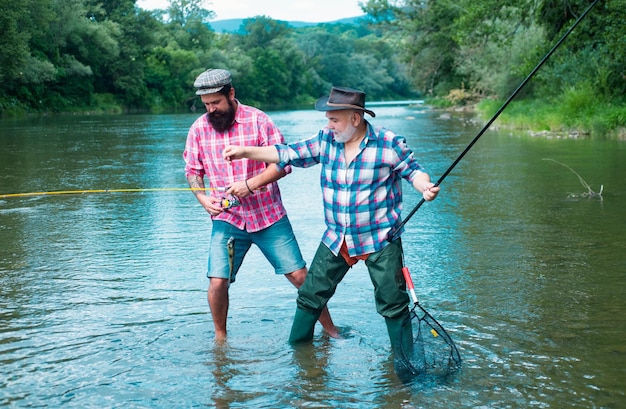 Padre e figlio maturo pescatori a pescare con una canna da pesca sul fiume amici uomini felici e eccitati