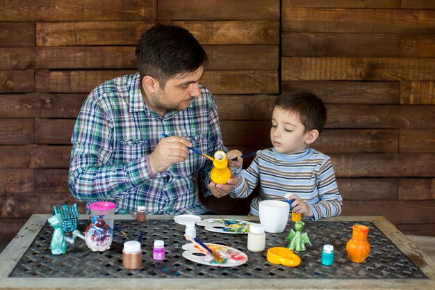 Padre e figlio nello studio di dipingere un vaso.