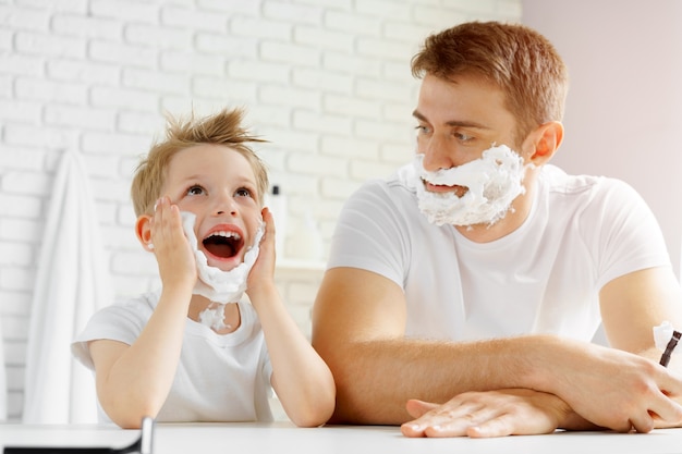 Padre e figlio piccolo che si divertono con la schiuma da barba