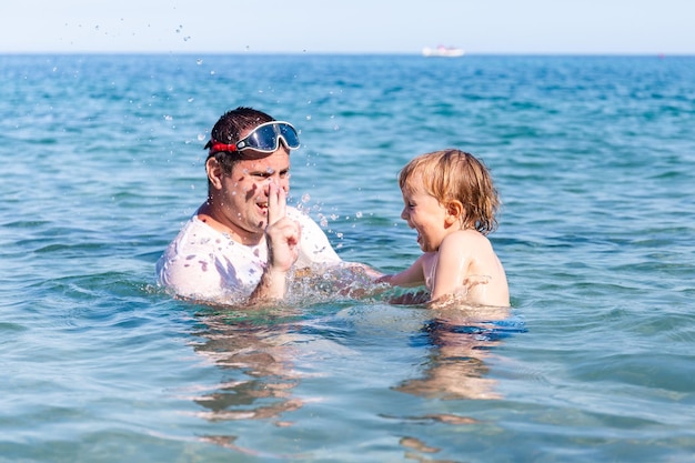 Padre e figlio piccolo divertendosi a nuotare e giocare insieme nell'acqua di mare durante le vacanze estive Legami familiari Vacanze al mare