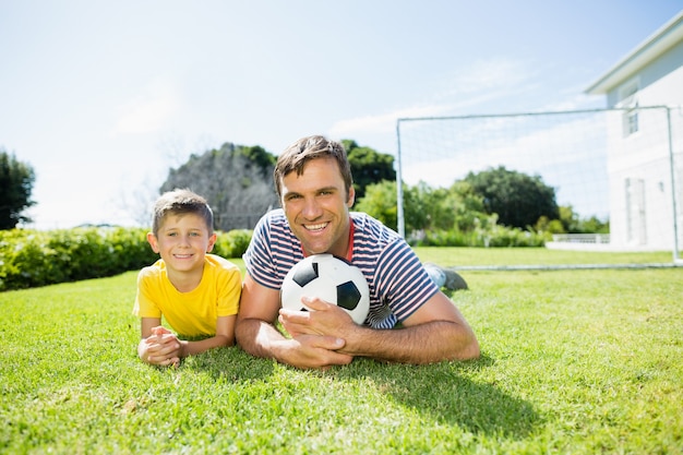 Padre e figlio sdraiati sull'erba nel parco in una giornata di sole