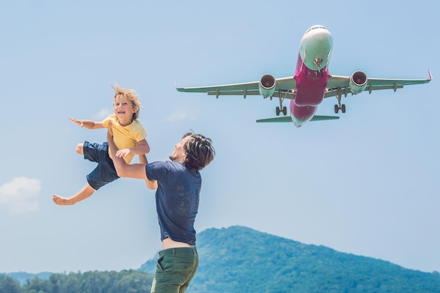 Padre e figlio si divertono sulla spiaggia a guardare gli aerei in atterraggio che viaggiano su un aereo con