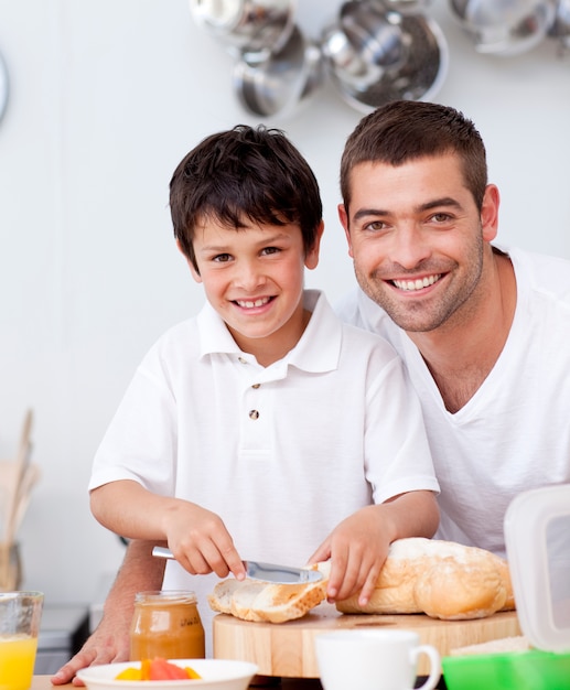 Padre e figlio sorridenti che preparano un pane tostato