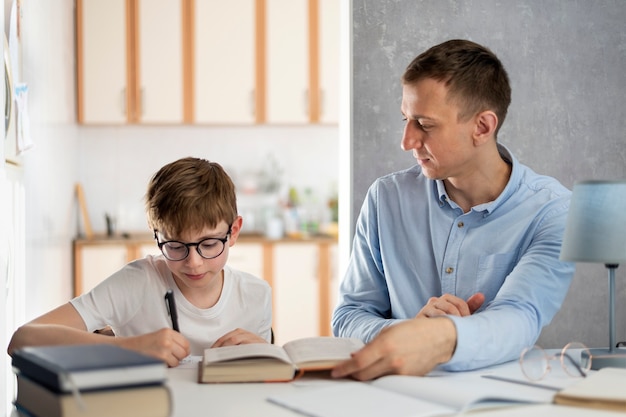 Padre e figlio stanno facendo i compiti. Il tutor del giovane insegnante sta studiando con il ragazzo. Ragazzo adolescente con gli occhiali scrive su un taccuino