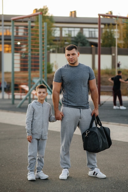 Padre e figlio stanno sul campo sportivo dopo l'allenamento durante il tramonto