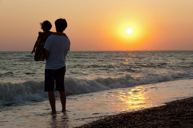 Padre e figlio sulla spiaggia al tramonto