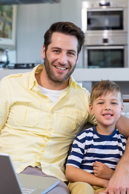 Padre e figlio usando il portatile sul divano