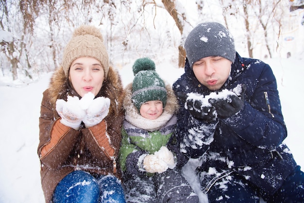 Padre e madre camminano con il figlioletto in una foresta d'inverno.