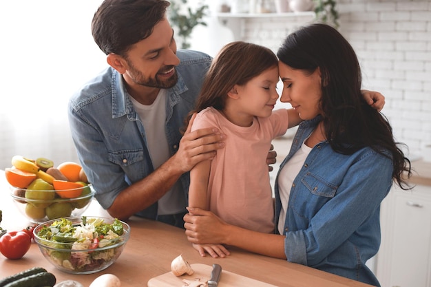 Padre e madre che abbracciano la figlia sul ritratto della cucina