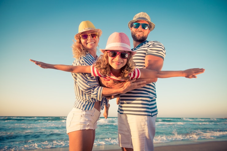 Foto padre e madre che tengono il bambino in braccio in spiaggia