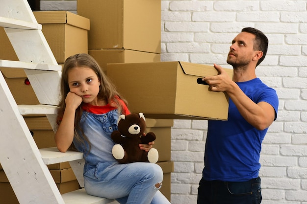 Padre e ragazza con la faccia triste o annoiata che si trasferiscono