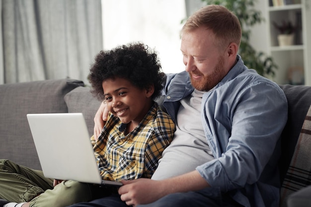 Padre e suo figlio adottivo utilizzando il laptop