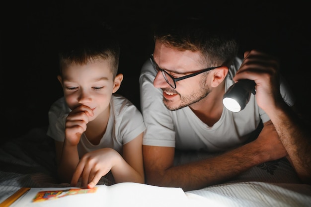 Padre e suo figlio piccolo che leggono la favola della buonanotte a casa