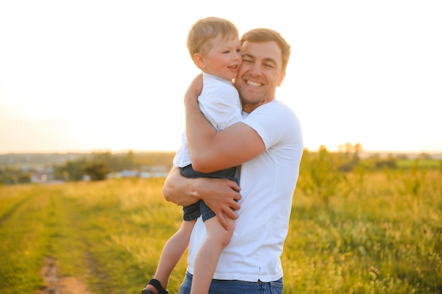 Padre felice che gioca con il figlio sullo sfondo del tramonto Il concetto di festa del papà