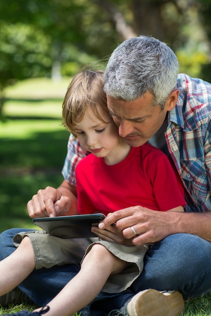 Padre felice che utilizza il pc della compressa con suo figlio