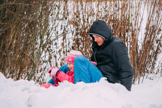 Padre felice con slittino bambino in un parco invernale.