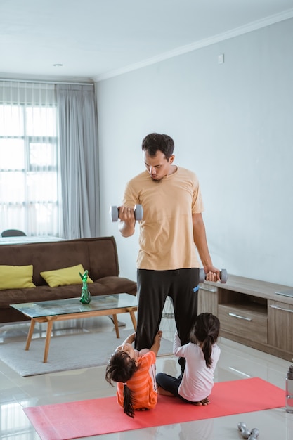 Padre felice e bambino che fanno esercizio insieme. ritratto di sano allenamento familiare a casa. ragazzo disturba suo padre mentre fa sport