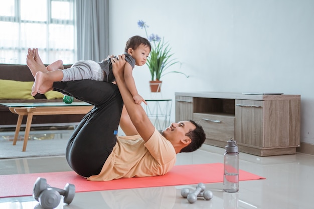 Padre felice e bambino che fanno esercizio insieme. ritratto di sano allenamento familiare a casa. uomo e suo figlio sport